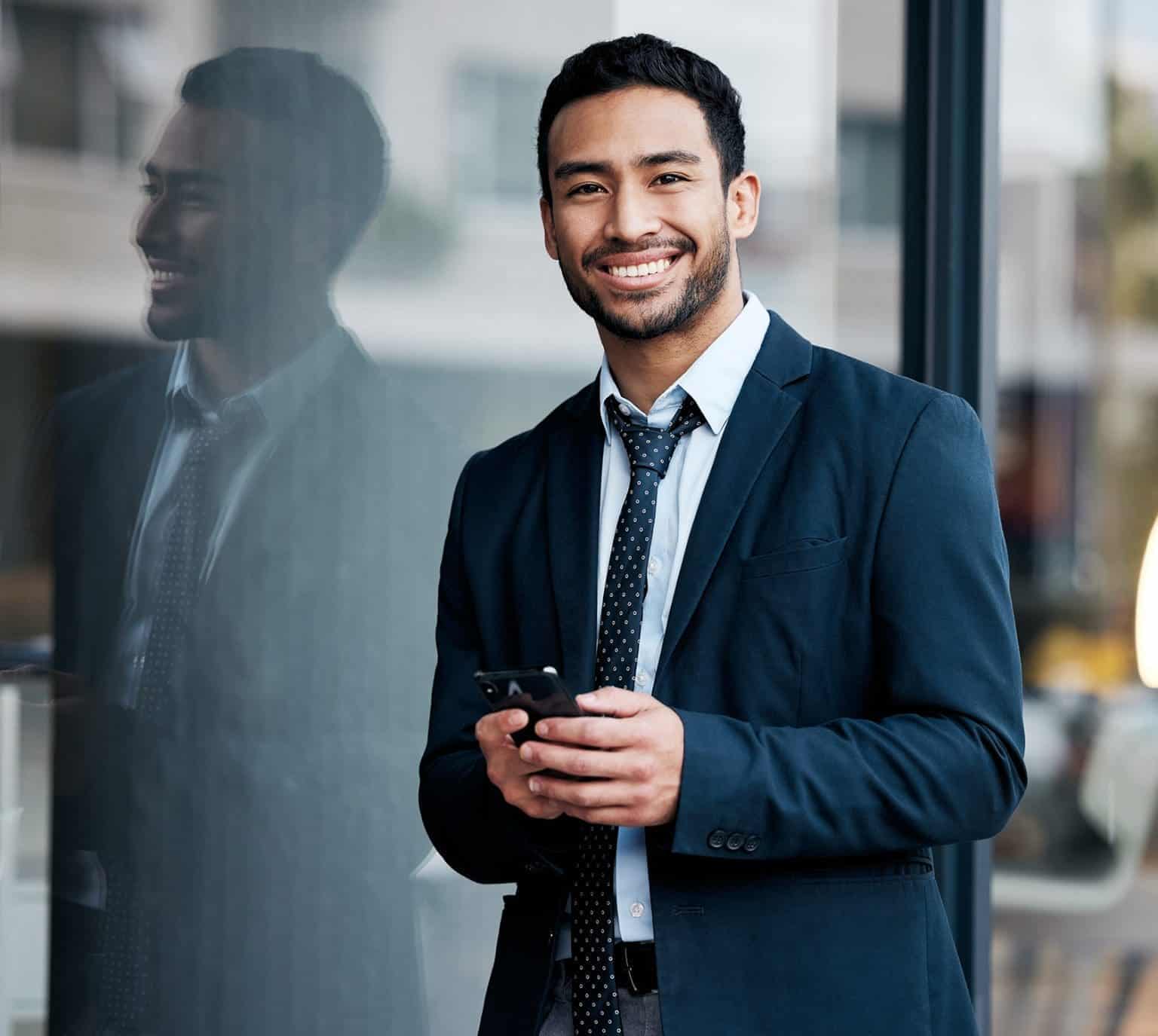 Shot of a handsome young businessman standing in the city and using his cellphone